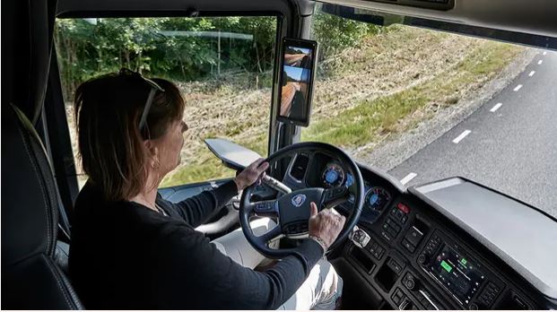 Kort inifrån en lastbilshytt med en kvinna som lastbilschaufför.